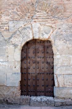Simple wooden doorway with studded wooden door in gardens of Alhambra palace Granada, Spain