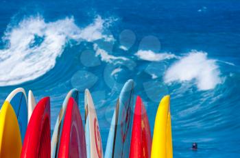 Dramatic powerful waves break over beach with stack of surfboards ready to go on beach at Lumaha'i, Kauai, Hawaii