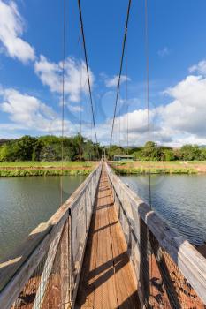 Wide angle view across the famous wooden suspension swinging bridge to cross the river in Hanapepe Kauai