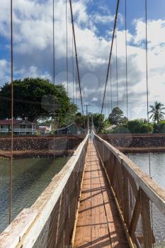 Wide angle view across the famous wooden suspension swinging bridge to cross the river in Hanapepe Kauai