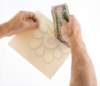 Stack of fifty and twenty US dollar bills being put in envelope by senior caucasian hands as though offering as a gift