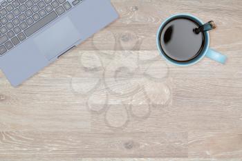 Tidy organized desk top with laptop and cup of coffee or tea on an oak wooden table for designer workspace