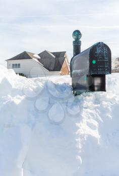 Piles of snow bury the mail box of a modern single family house after blizzard and snow drifts