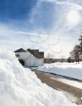 Piles of snow after the driveway to a modern single family house has been cleared after blizzard and snow drifts