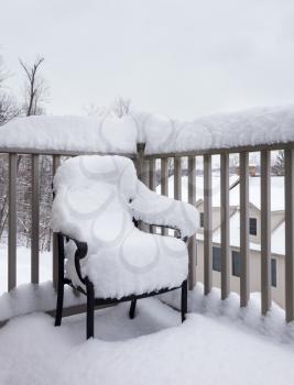 Outdoor garden chair or seat on balcony and covered with snow so it looks like a snow body or snowman sitting in the chair