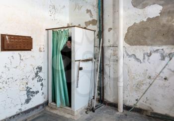 Senior man emerges from shower stall and curtain inside Trans-Allegheny Lunatic Asylum in Weston, West Virginia, USA