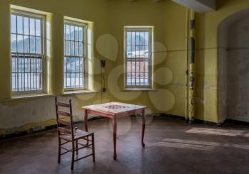 Single chair and game table inside Trans-Allegheny Lunatic Asylum in Weston, West Virginia, USA