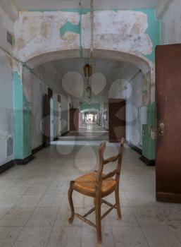 Chair looking down long corridor inside Trans-Allegheny Lunatic Asylum in Weston, West Virginia, USA