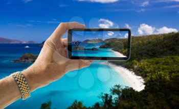 Tourist taking photo on smartphone of Trunk Bay beach on St John US Virgin Islands
