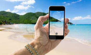 Tourist taking photo on smartphone of Anse Marcel beach on St Martin Sint Maarten Caribbean