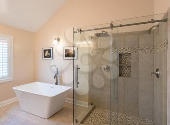 Interior of modern bathroom with standalone tub bath and walk in double tiled shower with rain head