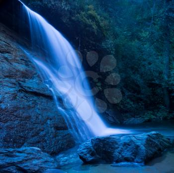 Moonlit view of the blurred motion water of Silver Run falls cascade into shaded pool near Cashiers North Carolina