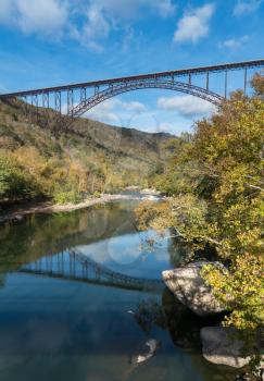 Reflections in the calm water under the high arched New River Gorge bridge in West Virginia