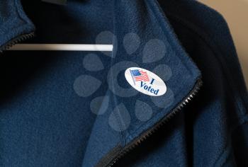 I Voted sticker with USA flag on blue jacket on hanger after getting home from the vote for President