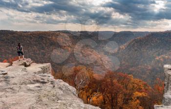 Young female woman overlooks the hills covered with fall trees from Raven Rock overlook at Coopers Rock State Forest West Virginia