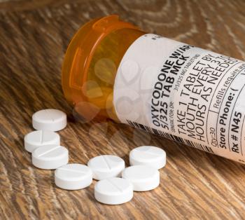 Close photo of prescription bottle for Oxycodone tablets and pills on wooden table for opioid epidemic illustration