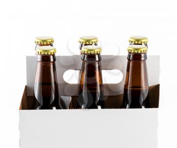 Six beer bottles in cardboard container with gold caps with side of carrier facing camera