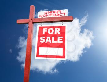 Realtor installed for sale sign for house or real estate set against blue sky and clouds