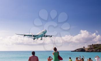 International jet flight lands over Maho beach at Princess Juliana airport on Caribbean island of St Martin