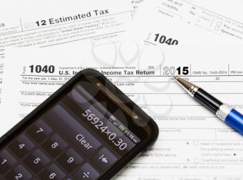 Tax form 1040 for tax year 2015 for US individual tax return with smartphone calculator