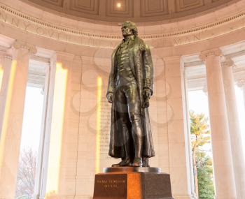 Bronze statue of Thomas Jefferson in Jefferson Memorial in Washington DC as setting sun illuminates interior of the monument