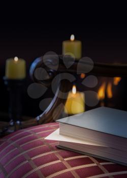 Envelope inserted into a book as a marker and left abandoned on a carved chair with firelight and candles in background to give a warm cozy winter feeling