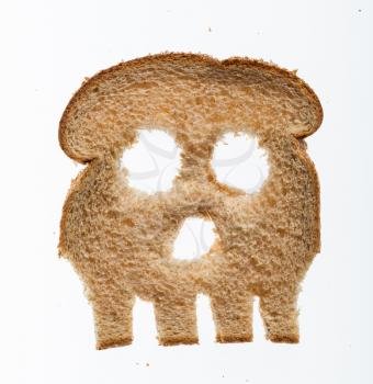 Skull shaped piece of bread cut from whole wheat loaf to illustrate danger from gluten in wheat products