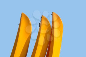 Three yellow prows of canoes or kayak with clipping path to allow easy isolation from blue sky behind the boats
