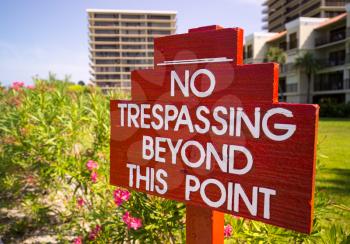 Large no trespassing sign in front of flower gardens in holiday resort or private apartments by beach in Florida