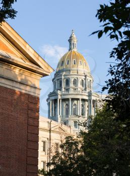 The gold leaf covered dome of the State Capitol Dome in Denver Colorado shortly after sunrise