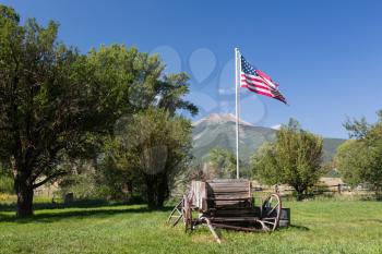 Farmyard and old horse pulled cart with US flag with Mount Princeton near Buena Vista Colorado