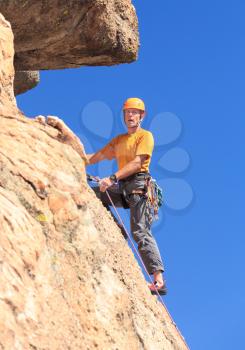 Senior male climber well equipped with cams and caribiners climbing on Turtle Rocks near Buena Vista Colorado