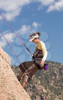 Senior female climber descending on belay assisted climb on Turtle Rocks near Buena Vista Colorado