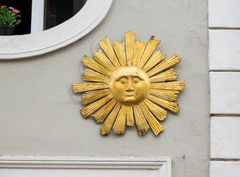 Gold colored wooden carving of the face of the sun with rays and sunburst on wall in the medieval town of Regensburg, Bavaria, Germany