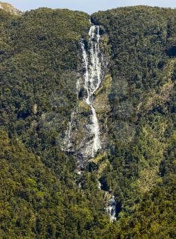 Water cascading down the rock formation in Doubtful Sound on South Island of New Zealand  with multiple waterfalls