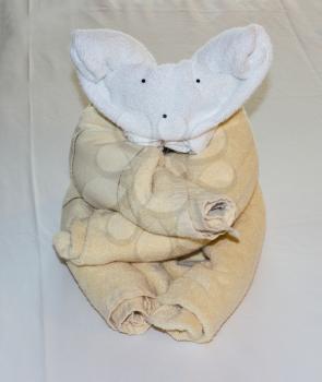 Unusual animal shaped like a koala or teddy bear created from rolled and folded towels on top of bed sheets in hotel
