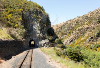 Railway track of Taieri Gorge tourist railway runs into a tunnel on its journey up the valley