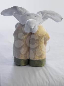 Unusual animal shaped like a elephant created from rolled and folded towels on top of bed sheets in hotel