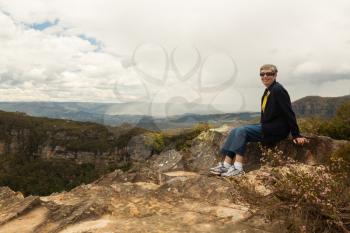 Senior Woman hiker sites at Landslide Lookout on Cliff Drive overlooking the majestic Blue Mountains near Sydney NSW Australia