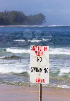 Warning sign no swimming in treacherous winter waters on Tunnels Beach in Kauai Hawaii