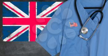 Blue doctor scrubs shirt and stethoscope hang empty in front of British flag. Illustration of medical staff coming from USA or America to staff national health service