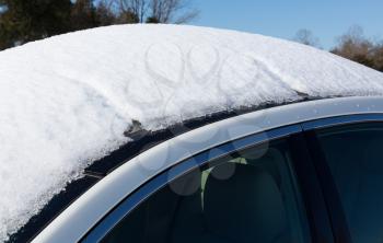 Deep snow piled high on top of white four door sedan car in rural setting