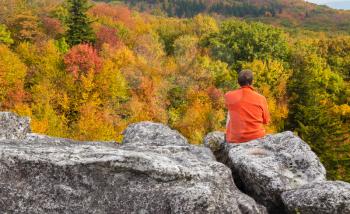 Red autumn leaves across Dolly Sods Wilderness area in West Virginia with hiker admiring the view