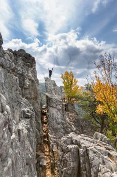 Young climber reaches the summit of the rocky granite mountain top of Seneca Rocks in West Virginia