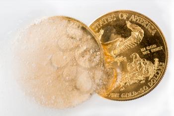 Gold eagle one ounce coin emerging from a frozen ice block to illustrate concept of gold coming out of deep freeze and price going to rise