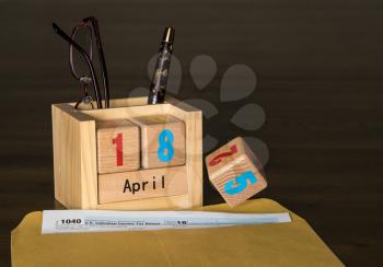 Wooden letters in calendar with Form 1040 income tax for 2016 showing tax day for filing is April 18 2017 instead of the normal 15th. Number 5 is shown falling to table