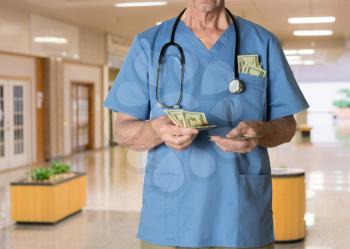 Senior caucasian doctor in scrubs in hospital counting cash and expecting payment for medical services