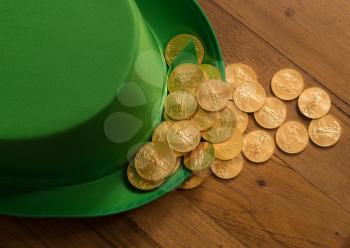 Treasure of pure gold coins inside a green velvet hat on wooden table to celebrate luck on St Patrick's Day of March 17th