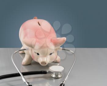 Large pink piggy bank on vet table with stethocope to illustrate condition of savings or retirement