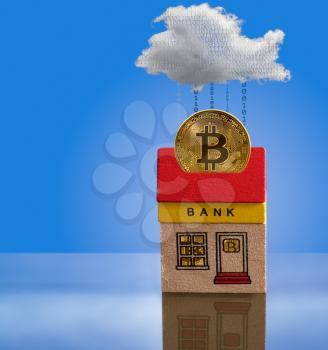 Toy brick bank building with bitcoins inside the windows and one coin emerging from roof into cyberspace. Illustration of the importance of modern techology to banking